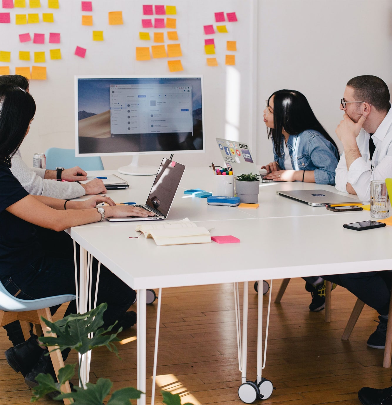 image of two women and a man working with laptops in an office casually